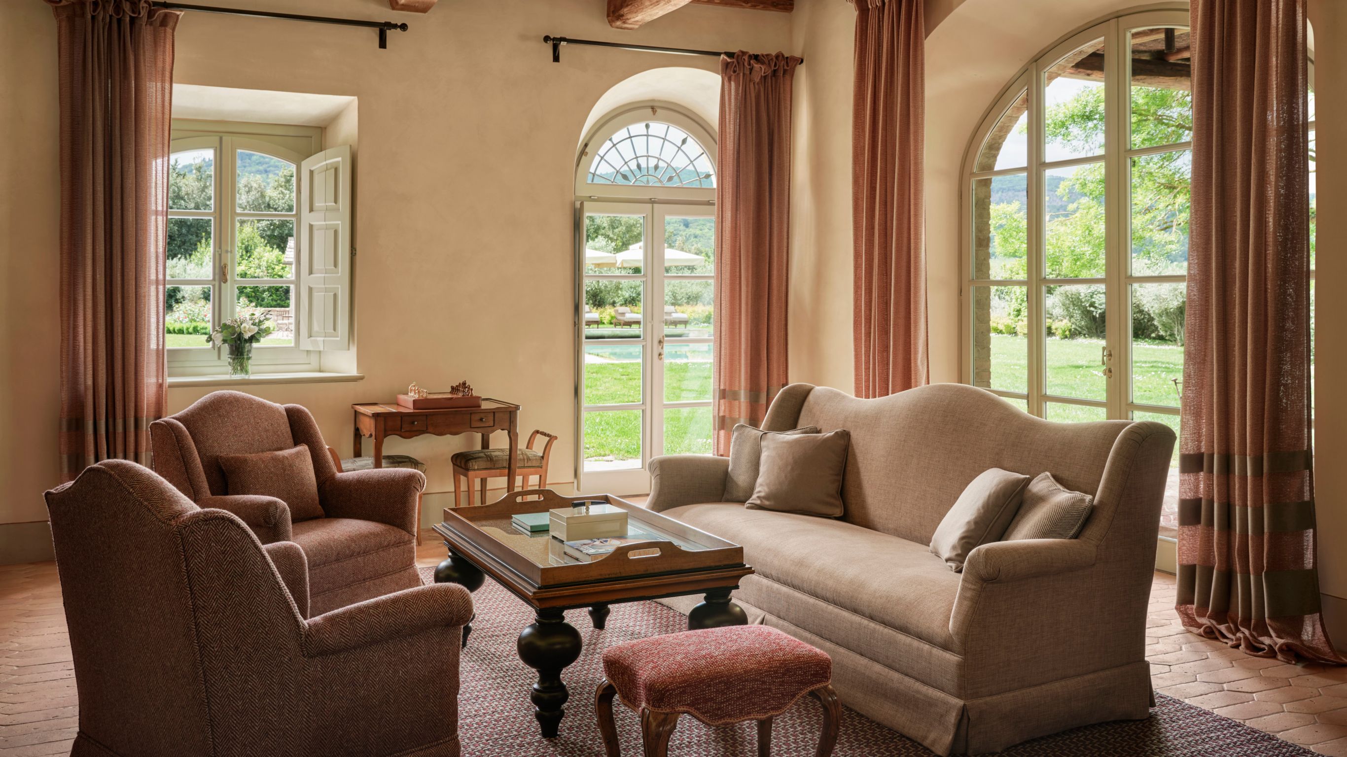 A living room with plush seating and arched glass doors opening to a garden view